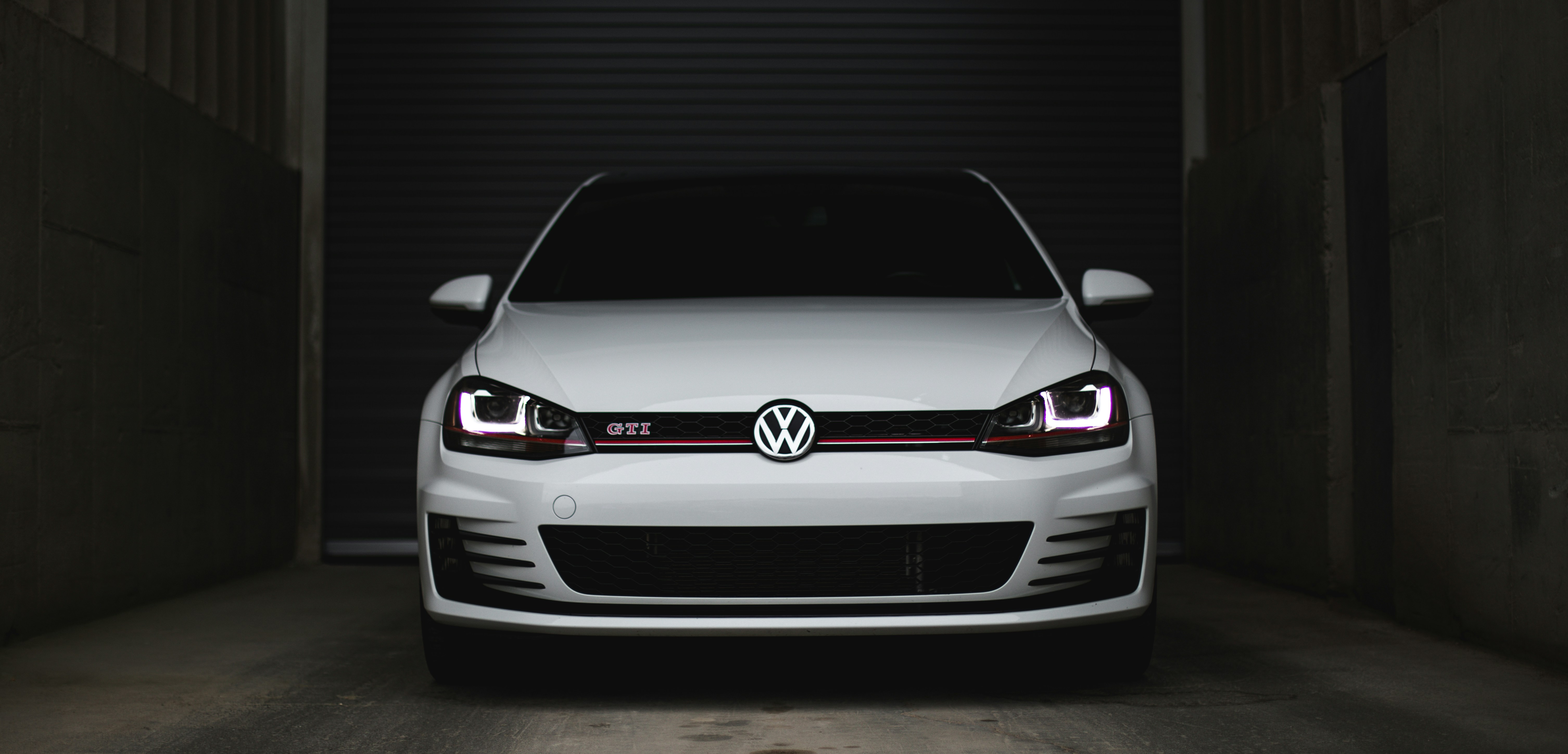 თეთრი Volkswagen Tiguan მთის გზაზე საქართველოში, ყაზბეგთან, ფონზე კავკასიონის მწვერვალები